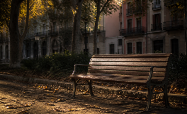 Banc de fusta solitari en un parc del Poble Sec de Barcelona al capvespre amb llum daurada filtrant-se entre els plataners: la buidor de la pèrdua després d'una separació